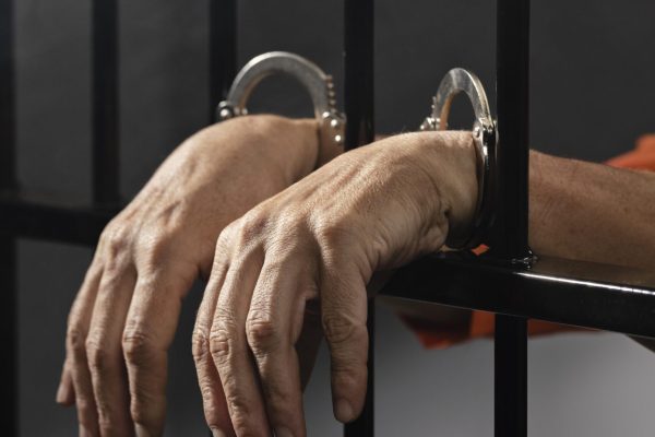 close-up-hand-wearing-cuffs-jail close-up-hand-wearing-cuffs-jail
